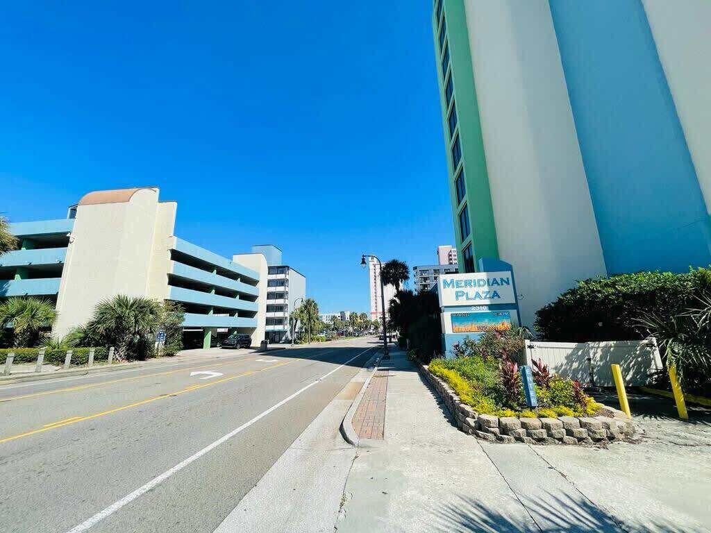 Une vue de rue avec une enseigne « Meridian Plaza », un parking à plusieurs étages et des bâtiments modernes.