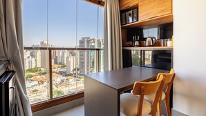 A modern kitchen with a large window, wooden cabinets, and a dining area with a table and chairs. - DVN - D'Oru Vila Nova Conceição by Anora (São Paulo)