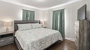 Een slaapkamer met een bed, nachtkastjes, een dressoir en een televisie.