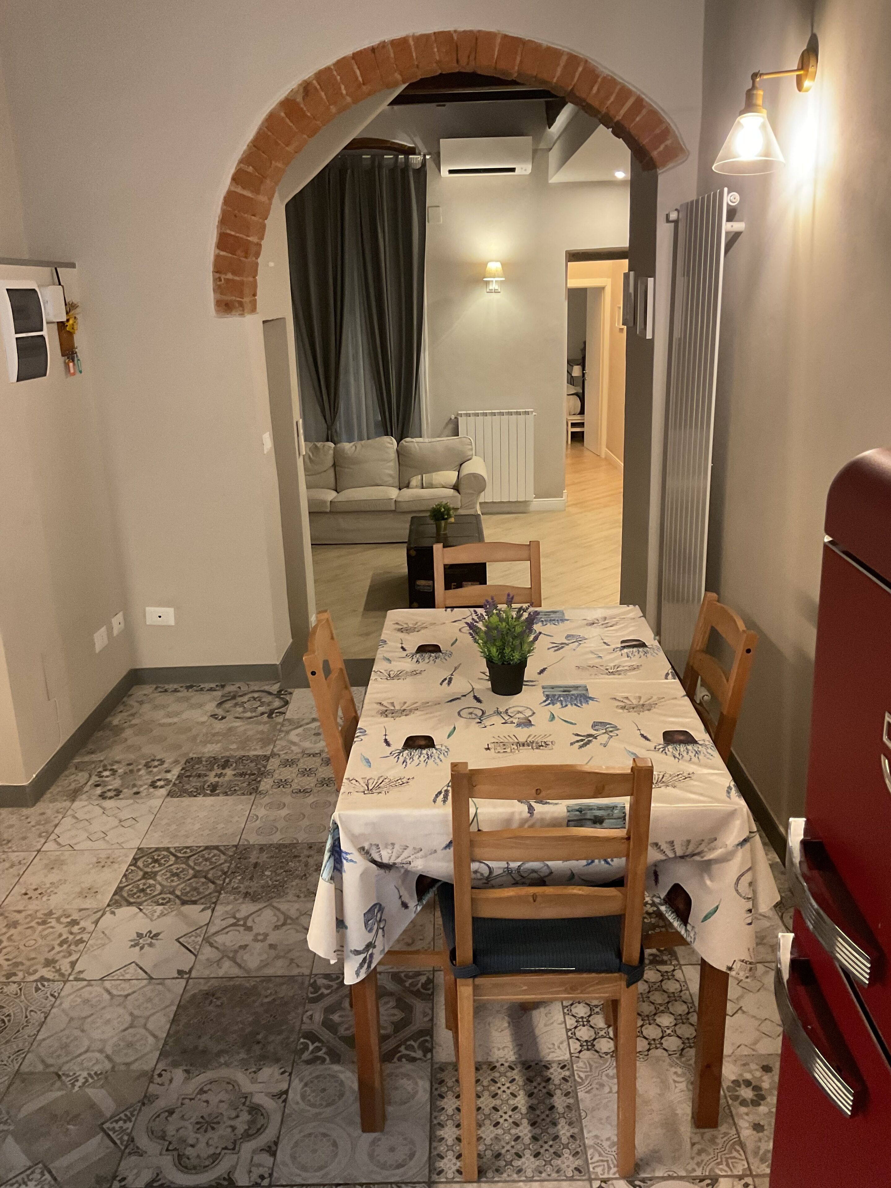 A dining area with a table set for four, a potted plant, and a red appliance in the background.