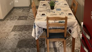 En matplats med ett bord dukat för fyra personer, en krukväxt och en röd apparat i bakgrunden.