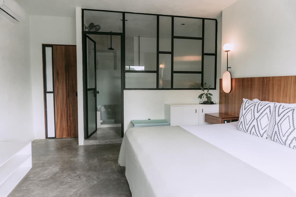 A modern bedroom with a bed, a nightstand, a dresser, and a walk-in closet.