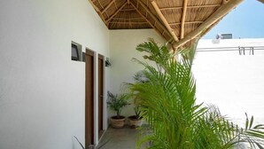 A covered outdoor area with a thatched roof, potted plants, and a view of the sea. - Casa Pia Sayulita (Sayulita)