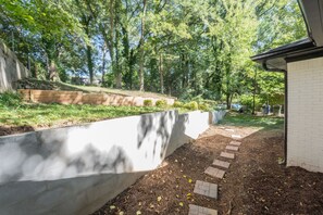Enjoy the serene surroundings of this beautifully landscaped outdoor space, featuring a brick pathway and lush greenery.