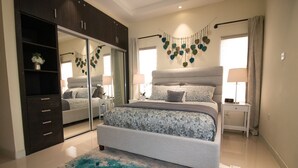 Quarto com cama grande, guarda-roupa, espelho e guirlanda decorativa em formato de coração.