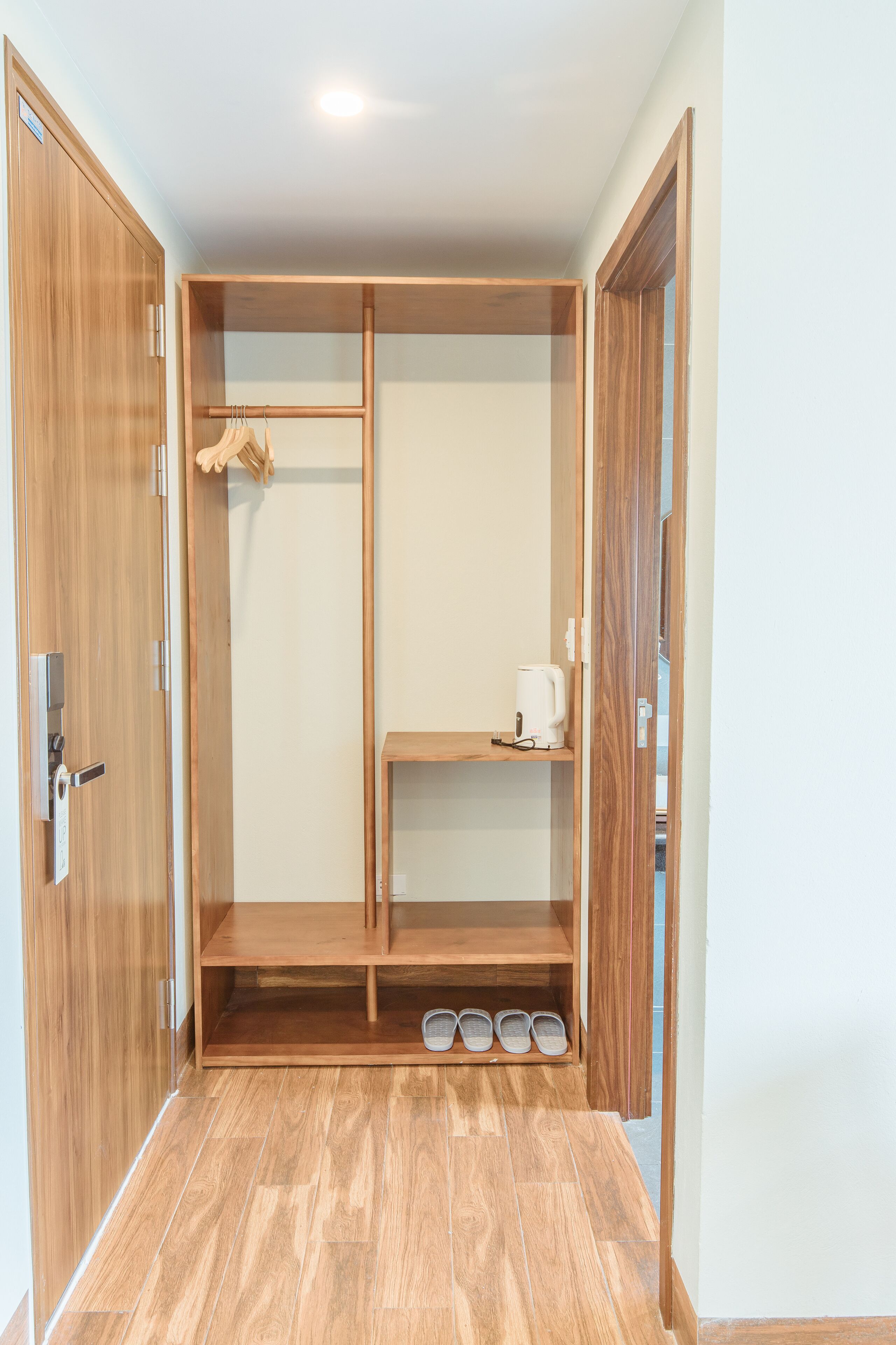 A walk-in closet with wooden doors, shelves, and a shoe rack.