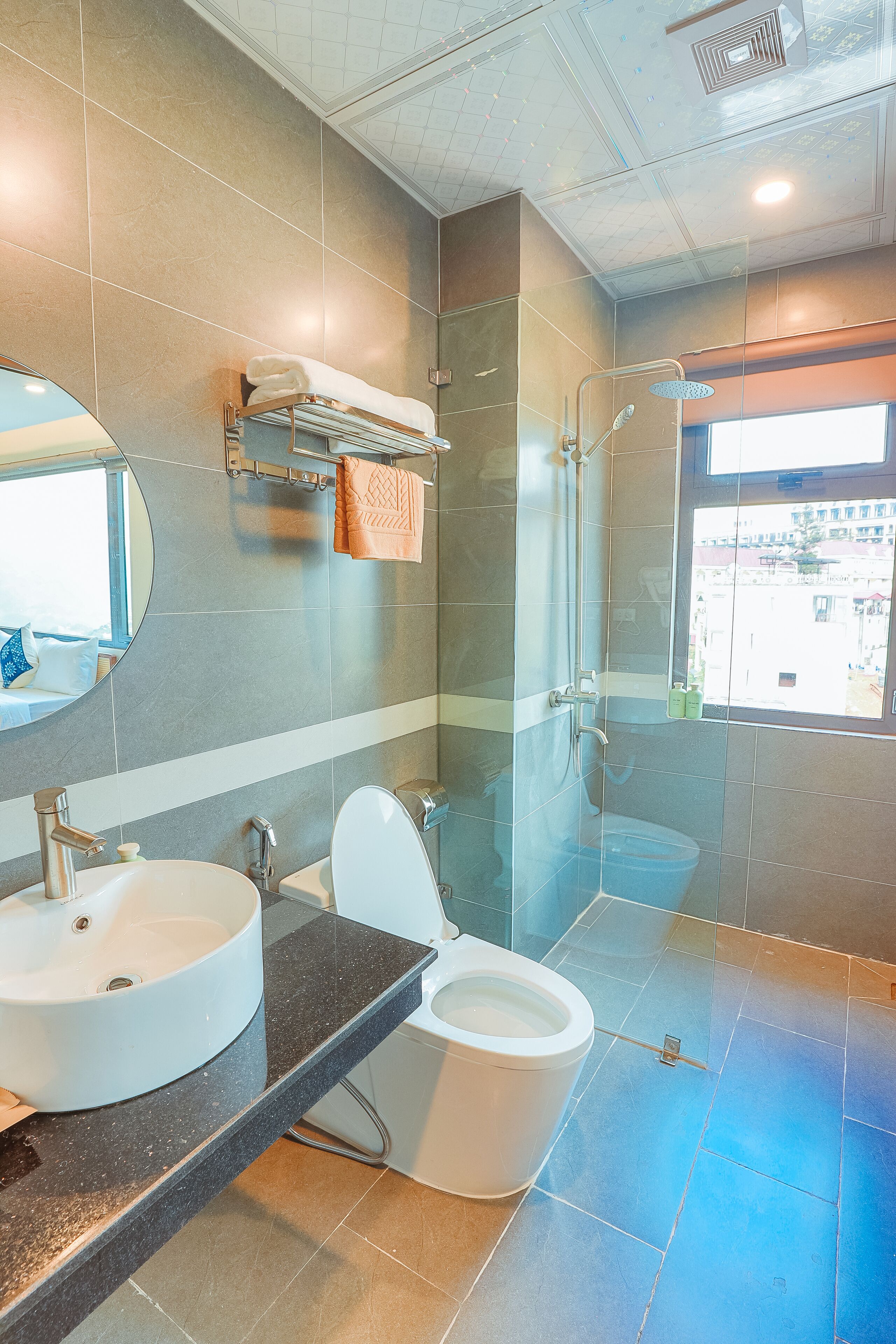 Un baño moderno con ducha de vidrio, inodoro blanco y un espejo grande sobre el lavamanos.