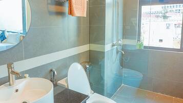 Un baño moderno con ducha de vidrio, inodoro blanco y un espejo grande sobre el lavamanos.