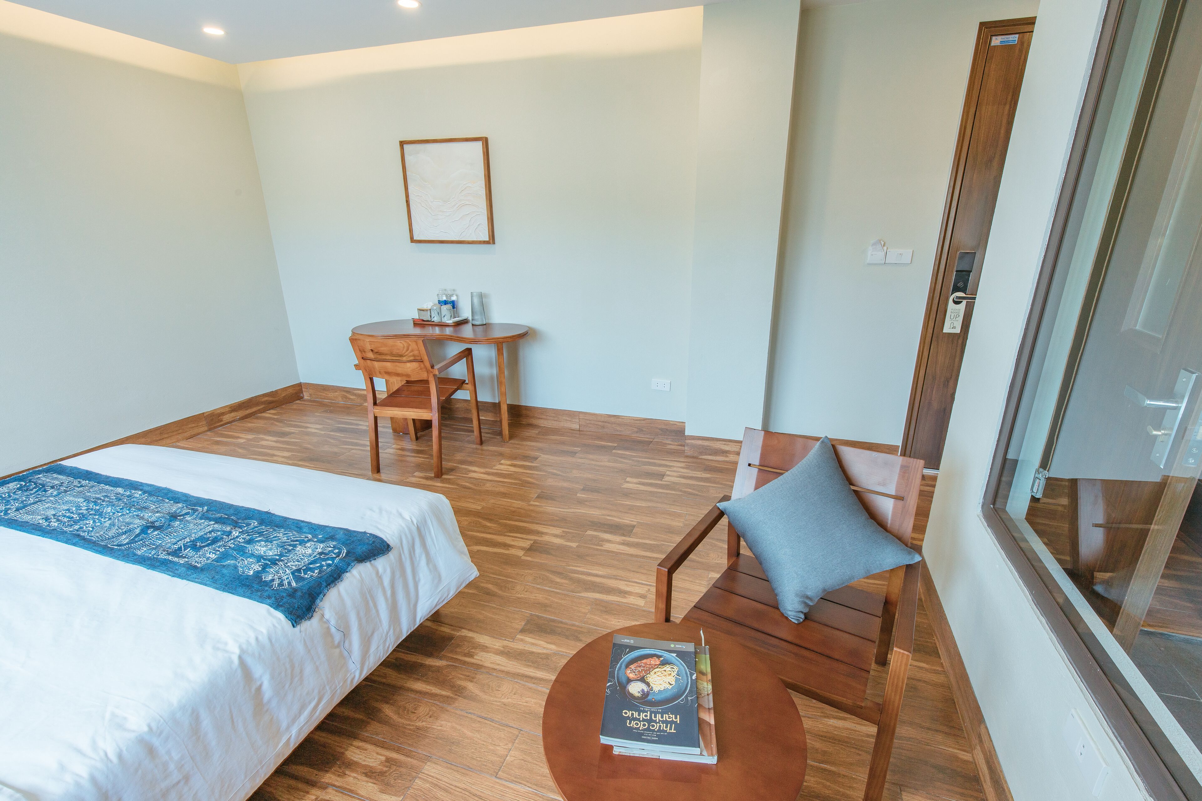 A hotel room with a bed, a desk, a chair, and a small table.