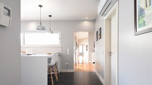 A modern kitchen with a central island, pendant lighting, and a view into the dining area. - Casa dos Infantes  (Vendas Novas)