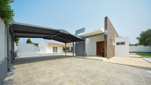 A modern building with a covered entrance, paved ground, and a clear sky. - Casa dos Infantes  (Vendas Novas)