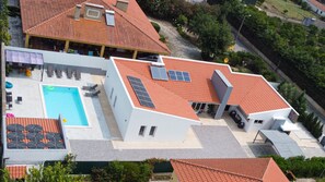 A modern building with a swimming pool, solar panels, and a covered patio area.