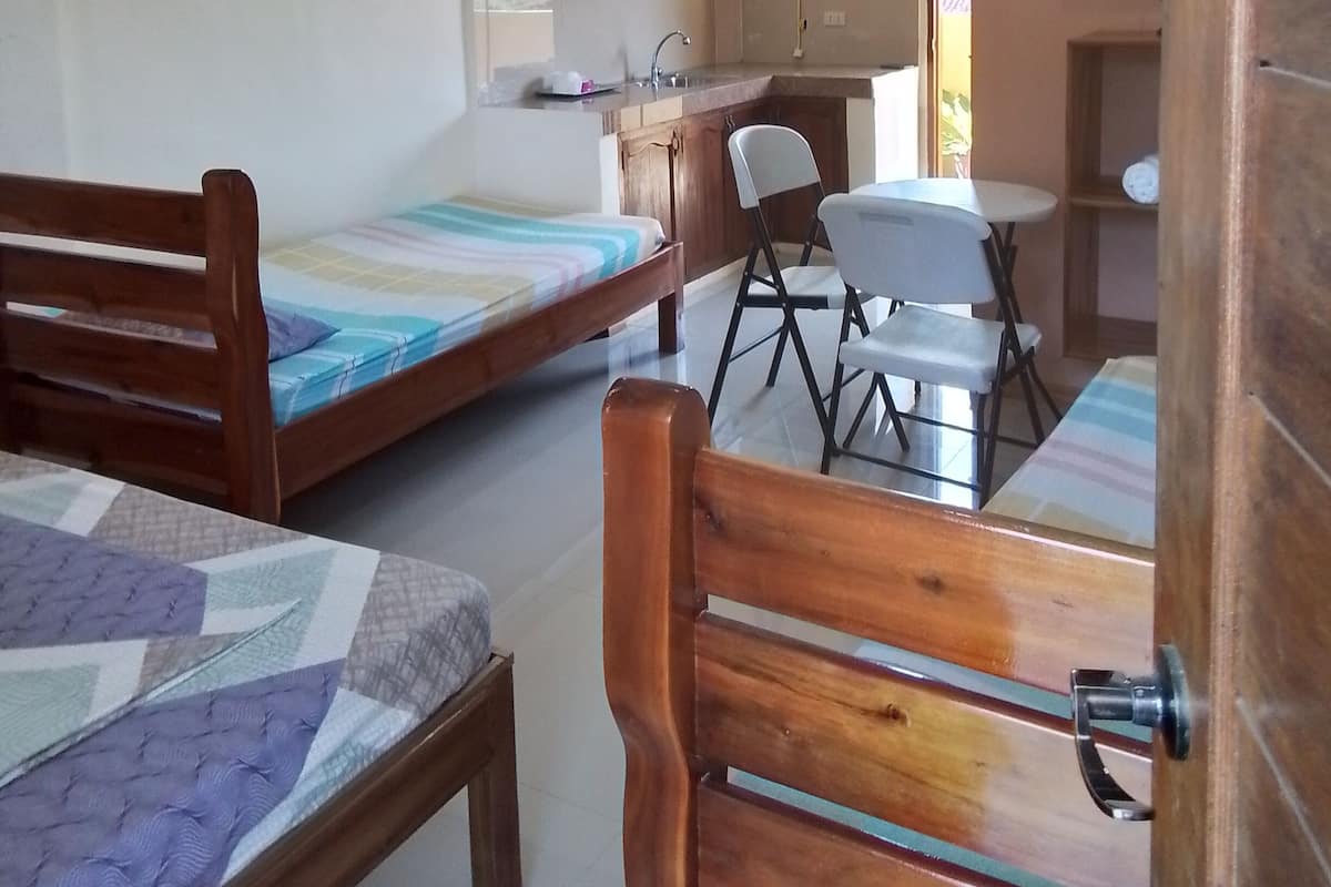Ein Zimmer mit einem Bett, einem Schreibtisch und einer Küchenzeile.