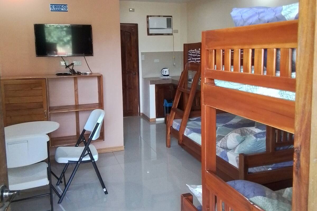 Ein Zimmer mit Stockbetten, einem Schreibtisch, einem Stuhl, einem Fernseher und einem Rauchverbot-Schild.