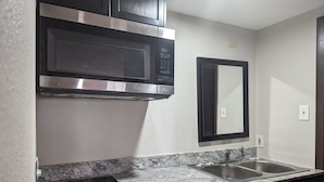 A kitchen with a stainless steel microwave, a double sink, and a built-in oven. - Budget Inn (Denison)