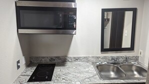 A kitchen with a built-in microwave, stove, and double sink. - Budget Inn (Denison)