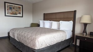 A hotel room with a large bed, a headboard, a bedside table with a lamp, and a framed picture on the wall. - Budget Inn (Denison)