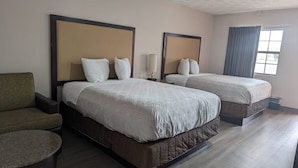A hotel room with two beds, a sofa, a round table, and a window with curtains. - Budget Inn (Denison)
