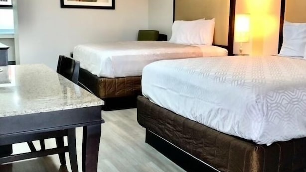 A hotel room with two beds, a desk, and a framed picture on the wall. - Budget Inn (Denison)