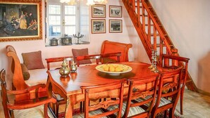 A dining room with a wooden table and chairs, a chandelier, and a staircase.
