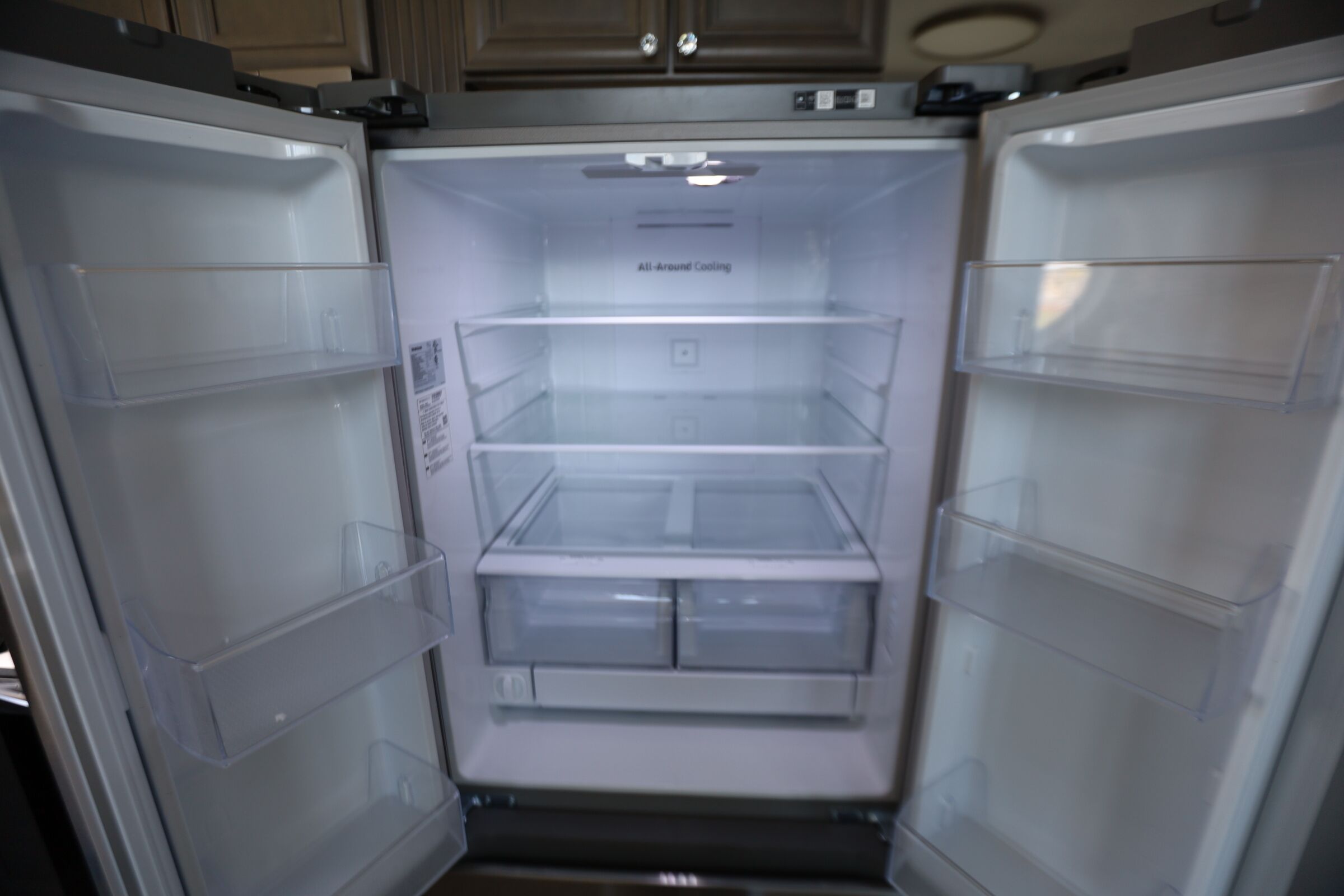 Un réfrigérateur ouvert, doté de plusieurs étagères transparentes et d’un panneau de commande.