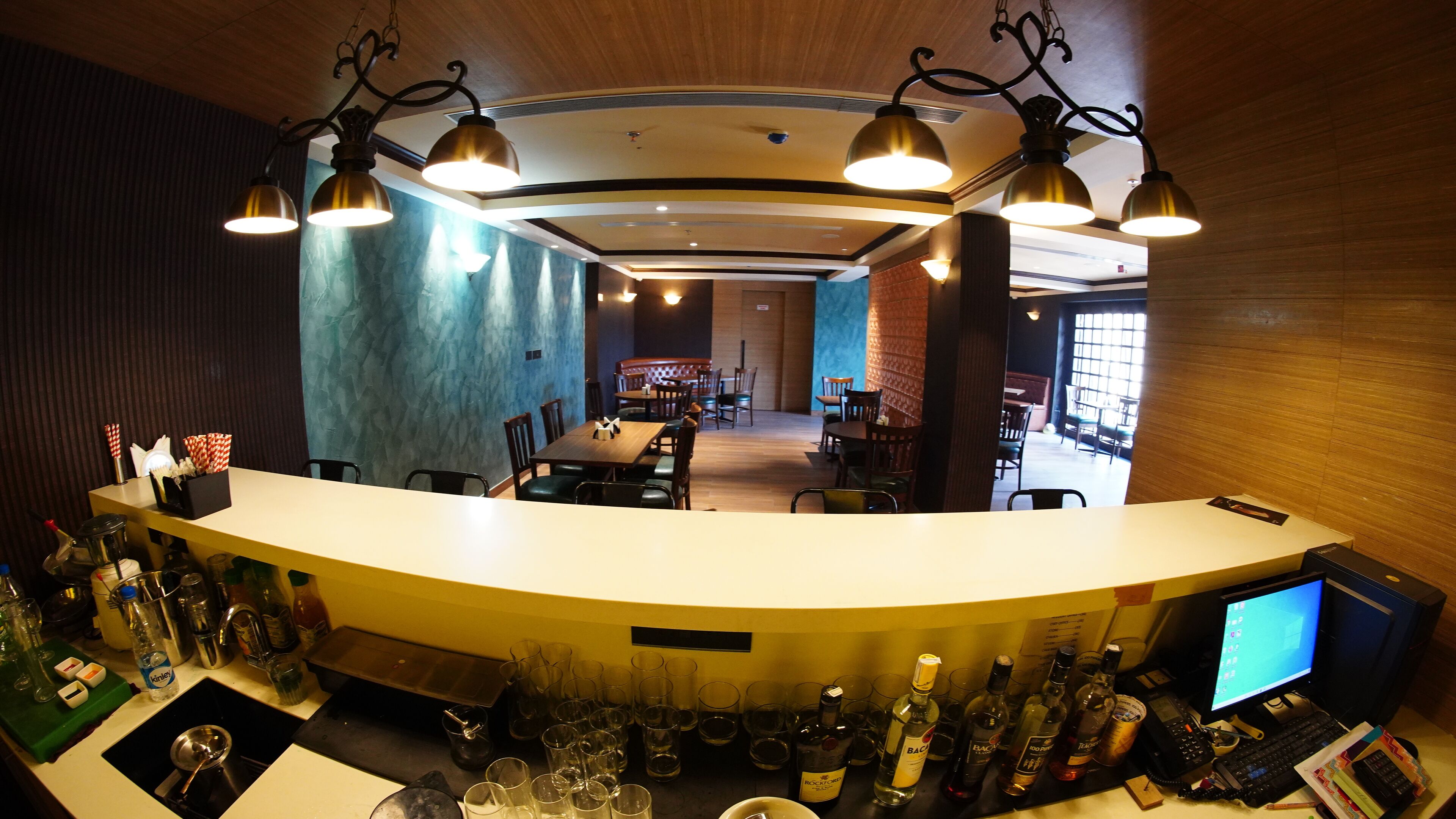 A bar area with a curved counter, multiple seating arrangements, and a variety of bottles and glasses.