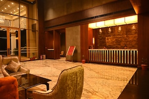 Un hall con mostrador de recepción, zona de estar y una pared de piedra.