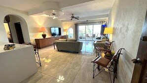 A spacious living area with a sofa, a dining table with chairs, a TV, and a ceiling fan. - Breathtaking Ocean views in Central of Old Town in Puerto Vallarta. (Puerto Vallarta)