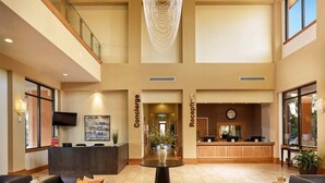 A spacious lobby with a reception desk, concierge and reception areas, a large chandelier, and a modern staircase. - Relaxing Regal Oaks Townhome (Kissimmee)