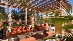 An outdoor patio area with wicker furniture, including sofas and a coffee table, under a wooden pergola. - Relaxing Regal Oaks Townhome (Kissimmee)