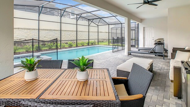 Ein überdachter Außenbereich mit Pool, Sitzgelegenheiten und Deckenventilator.