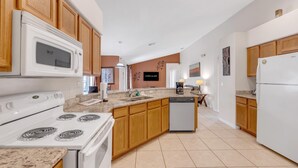 A kitchen with wooden cabinets, a white stove, a microwave, a dishwasher, and a granite countertop.