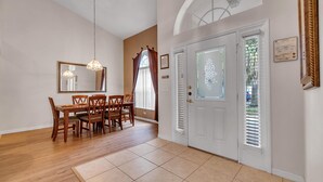 A dining area with a wooden table and chairs, a chandelier, and a door with frosted glass panels.