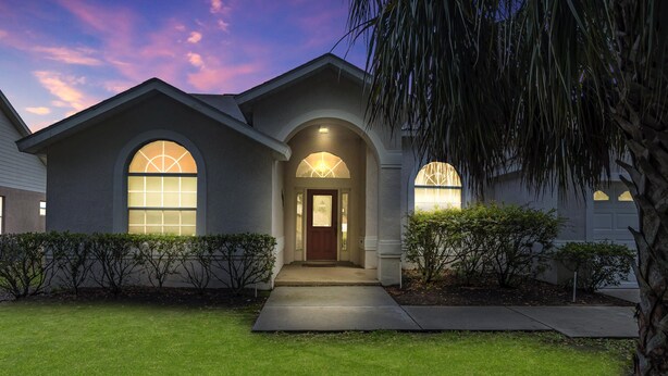 A residential house with a front entrance, a covered porch, and a well-maintained lawn.