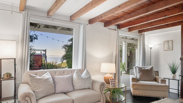 Una sala de estar con sofá, sillón, lámpara y vistas al exterior.