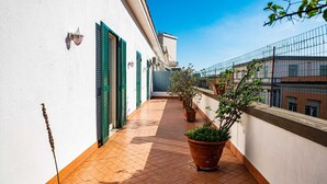 A narrow corridor with tiled flooring, green shutters, and potted plants. - Casa Toledo: Spazioso Attico in Centro , a 20 Metri Dalla Stazione Metro Toledo (Napoli)