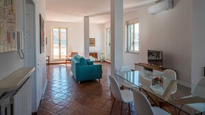 A spacious living area with a sofa, a glass dining table, and a TV. - Casa Toledo: Spazioso Attico in Centro , a 20 Metri Dalla Stazione Metro Toledo (Napoli)
