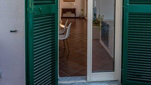A doorway with green shutters leading to an interior space with a tiled floor and a dining area with chairs. - Casa Toledo: Spazioso Attico in Centro , a 20 Metri Dalla Stazione Metro Toledo (Napoli)