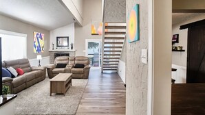 Un salon spacieux doté d’une cheminée, d’un escalier et offrant une vue sur l’extérieur.