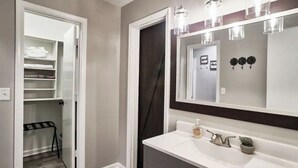 Une salle de bain avec un meuble-lavabo blanc, un grand miroir et un porte-serviettes.