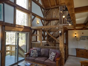 A spacious living area with a wooden staircase, a cushioned sofa with patterned cushions, and a wooden coffee table. - Ultimate On-Mountain Ski House! Private 3 Bedroom + Loft, 200' from Trail, Sauna (Killington)
