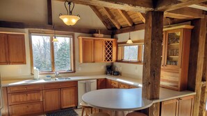 Eine Küche mit Holzausstattung, einer zentralen Kochinsel mit Sitzgelegenheiten und einem Fenster, das für natürliches Licht sorgt.