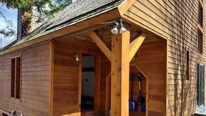 Eine Holzhütte mit überdachter Veranda, Ziegelfassade und Schornstein.