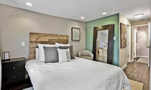 Relax in this serene bedroom with a large bed, nightstand, and mirror.