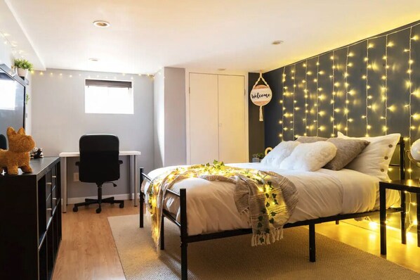 Cozy retreat with a made bed, desk, and warm string lights.