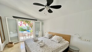 A bedroom with a bed, a ceiling fan, a small round table, and a view of the outside. - 58 -Villa, private swimming pool, close to the sea (Estepona)