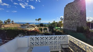 A terrace with a view of the sea, a stone tower, and a palm tree. - 58 -Villa, private swimming pool, close to the sea (Estepona)