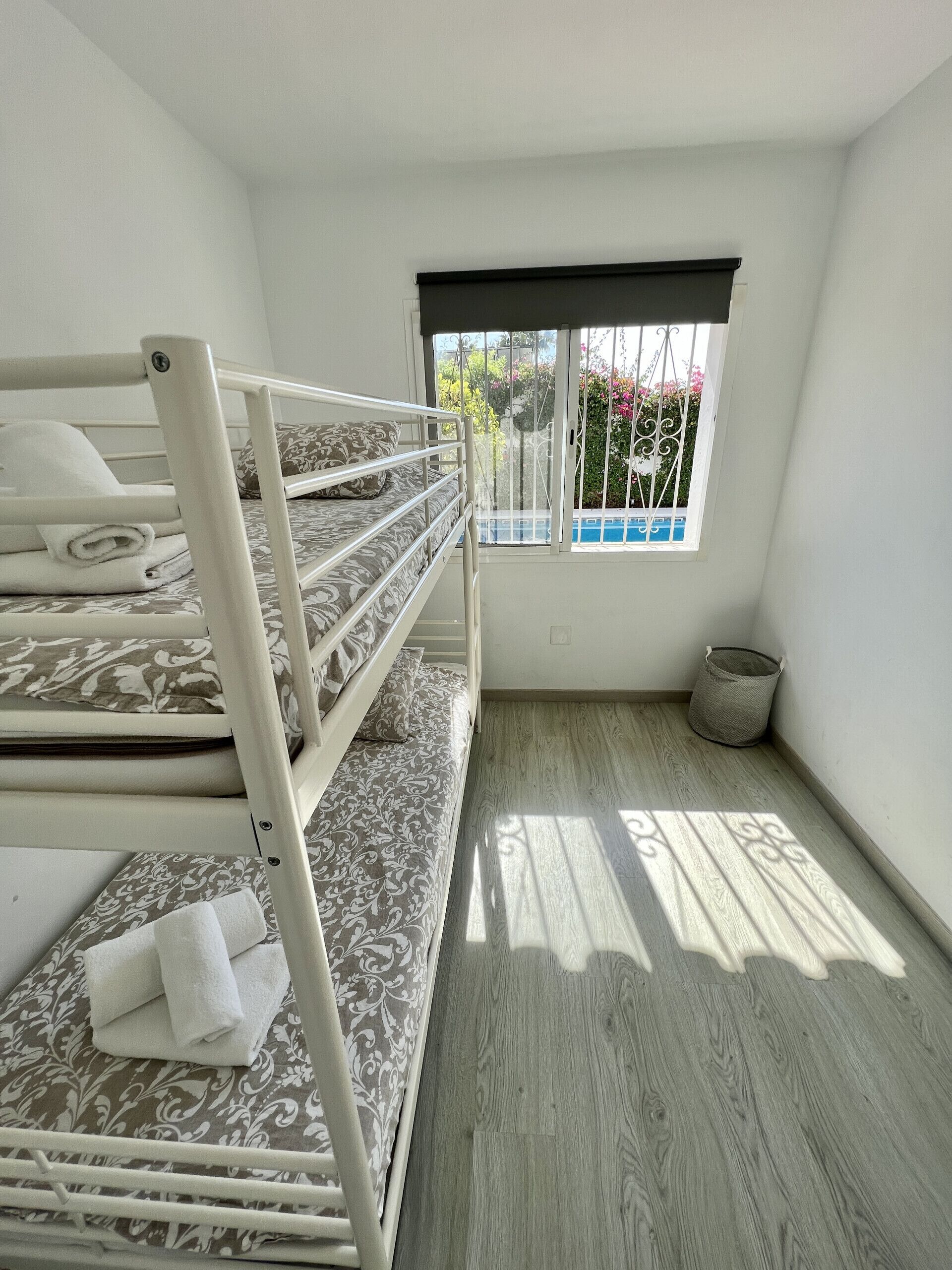 A room with bunk beds, a window with metal bars, and a wooden floor.