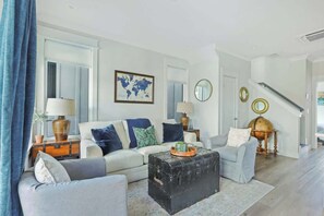 A living room with a sofa, armchairs, a coffee table, a globe, and a world map on the wall.