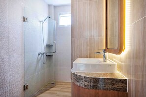 A modern bathroom with a glass shower enclosure, a vanity with a sink, and a mirror.
